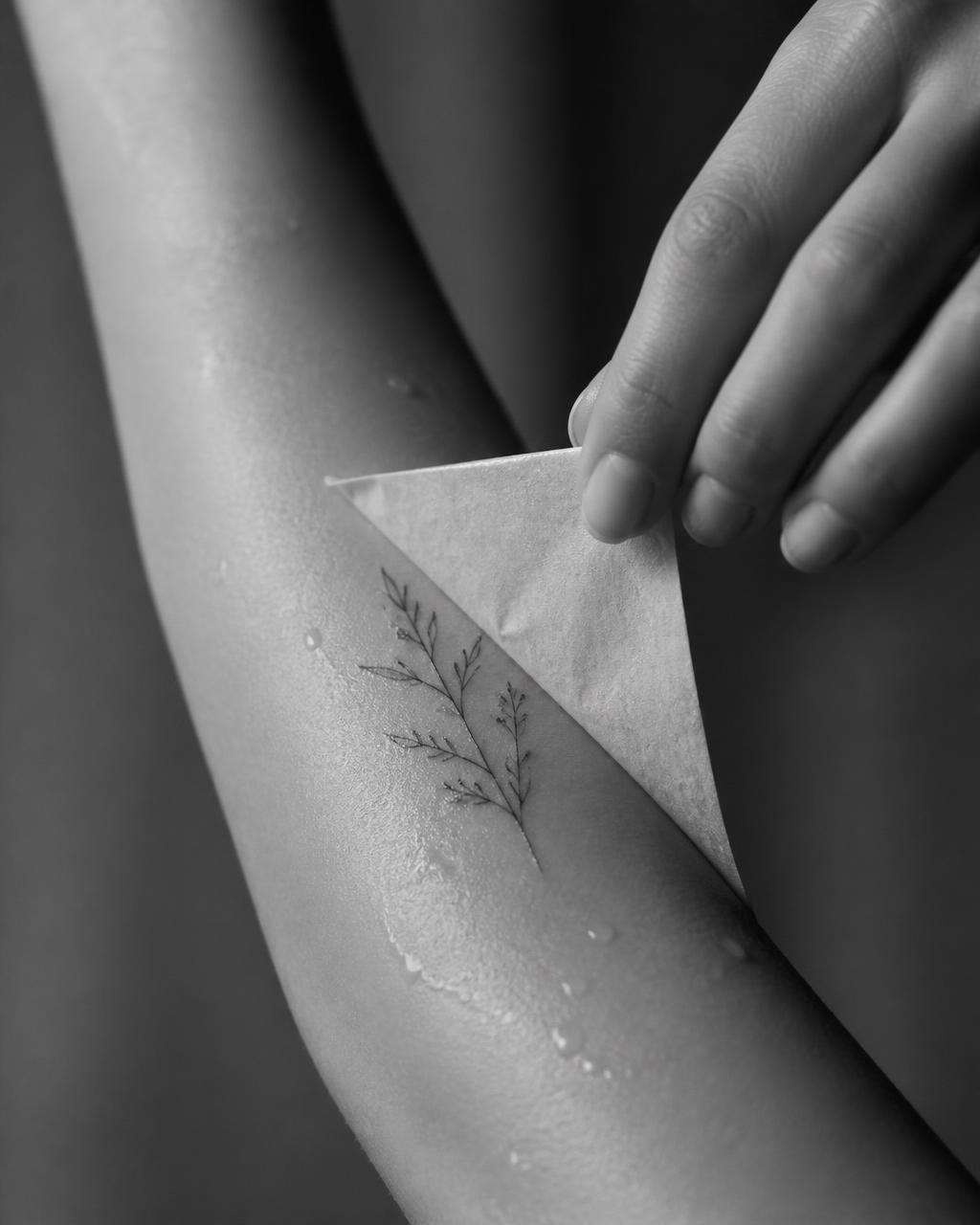 Peeling away the backing paper to reveal a finished semi-permanent tattoo